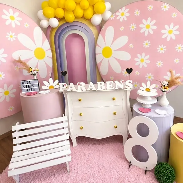 Kit de decoração montado com painéis de margaridas, arco de balões e cômoda provençal